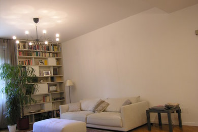 Diseño de sala de estar con biblioteca minimalista grande con paredes beige, suelo de madera clara, televisor colgado en la pared y suelo amarillo