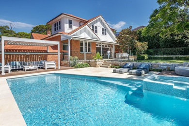 Mid-sized traditional two-storey brick house exterior in Sydney with a gable roof, a tile roof, a red roof and shingle siding.