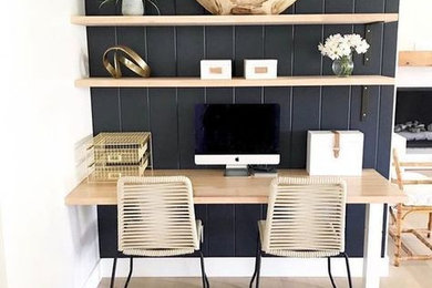 This is an example of a small modern home office in Surrey with a reading nook, blue walls, light hardwood flooring, a built-in desk and beige floors.