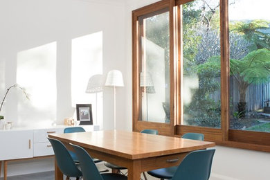 Photo of a mid-sized contemporary open plan dining in Wollongong with white walls and concrete floors.