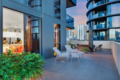 Expansive contemporary deck in Brisbane with a container garden and a roof extension.