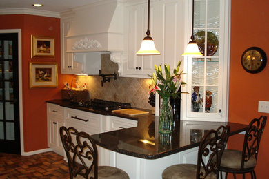 Inspiration for a mid-sized timeless brick floor eat-in kitchen remodel in Austin with an undermount sink, raised-panel cabinets, white cabinets, granite countertops, beige backsplash, stone tile backsplash, paneled appliances and a peninsula