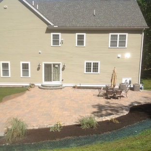 This is an example of a transitional sloped garden in Boston with a retaining wall and concrete pavers.