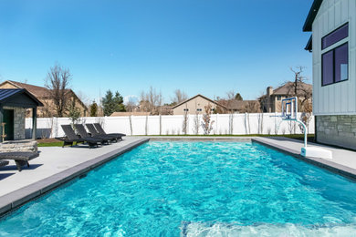 Imagen de piscina tradicional de tamaño medio rectangular en patio trasero con losas de hormigón