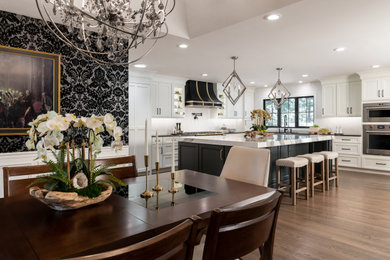 Example of a large eclectic medium tone wood floor and brown floor eat-in kitchen design in St Louis with shaker cabinets, white cabinets, quartz countertops, white backsplash, porcelain backsplash, black appliances, an island and black countertops
