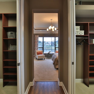 This is an example of an eclectic gender-neutral walk-in wardrobe in Orlando with dark wood cabinets and carpet.
