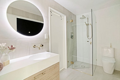 Design ideas for a small modern 3/4 bathroom in Brisbane with shaker cabinets, medium wood cabinets, a corner shower, a two-piece toilet, gray tile, porcelain tile, white walls, porcelain floors, an integrated sink, solid surface benchtops, grey floor, a hinged shower door, white benchtops, a niche, a single vanity and a freestanding vanity.