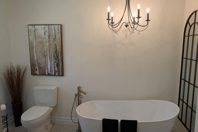 Freestanding bathtub - mid-sized contemporary double-sink, porcelain tile and beige floor freestanding bathtub idea in Toronto with shaker cabinets, black cabinets, granite countertops, a built-in vanity, a two-piece toilet, beige walls, an undermount sink and white countertops
