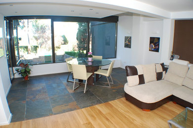 This is an example of a contemporary dining room in Madrid with slate floors and white walls.