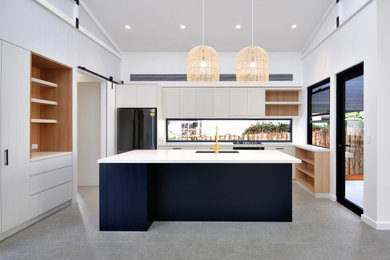 Photo of a large open plan kitchen in Sydney with an undermount sink, blue cabinets, black appliances, with island, grey floor and white benchtop.