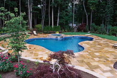 Inspiration for a traditional backyard custom-shaped pool in New York with decking.