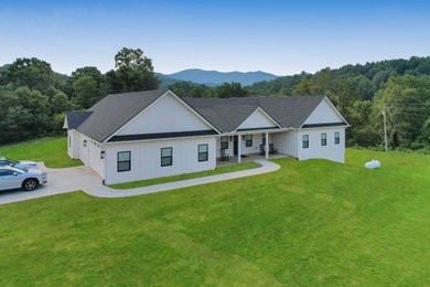 Inspiration for a mid-sized cottage white two-story wood and board and batten exterior home remodel with a shingle roof and a black roof