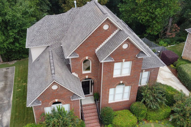 Large three-story brick and shingle house exterior photo in Birmingham with a shingle roof and a gray roof