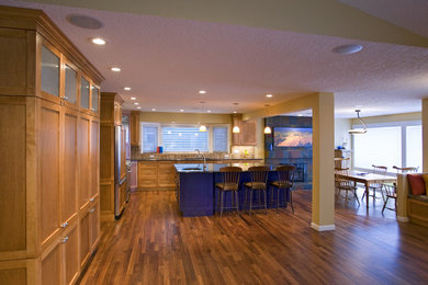 Inspiration for a large craftsman l-shaped medium tone wood floor and brown floor open concept kitchen remodel in Calgary with a double-bowl sink, shaker cabinets, light wood cabinets, beige backsplash, paneled appliances, an island and gray countertops