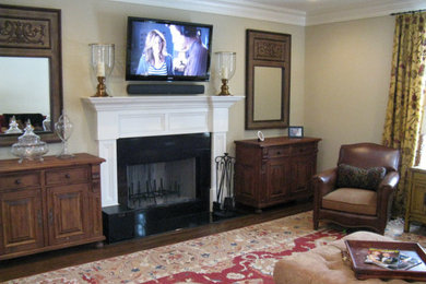 Inspiration for a timeless medium tone wood floor living room remodel in New York with beige walls, a standard fireplace, a plaster fireplace and a wall-mounted tv
