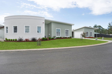 Photo of a mid-sized contemporary one-storey green duplex exterior in Other with mixed siding, a butterfly roof, a metal roof and a grey roof.