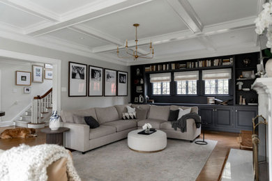 Inspiration for a large transitional enclosed medium tone wood floor, brown floor and coffered ceiling living room remodel in New York with beige walls, a standard fireplace, a wood fireplace surround and a wall-mounted tv