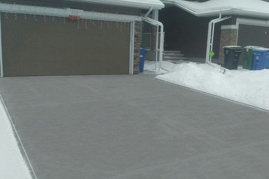 This is an example of a large modern full sun front yard concrete paver driveway in Calgary for winter.