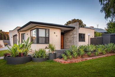 This is an example of a mid-sized midcentury one-storey concrete multi-coloured house exterior in Adelaide with a hip roof and a metal roof.