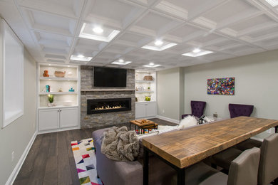 This is an example of a large transitional enclosed home theatre in Milwaukee with grey walls, medium hardwood floors, a wall-mounted tv and brown floor.