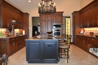 This is an example of a large traditional u-shaped eat-in kitchen in Miami with an undermount sink, raised-panel cabinets, medium wood cabinets, granite benchtops, stone tile splashback, stainless steel appliances, ceramic floors and with island.