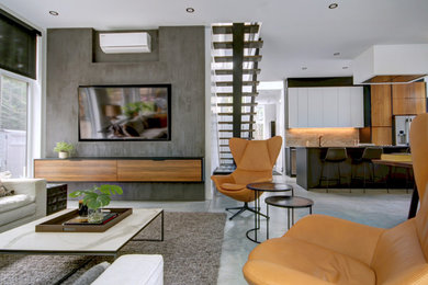 Стильный дизайн: большая парадная, двухуровневая гостиная комната в современном стиле с белыми стенами, бетонным полом, телевизором на стене и серым полом - последний тренд