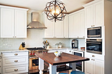 Mid-sized elegant u-shaped medium tone wood floor eat-in kitchen photo in Chicago with an undermount sink, raised-panel cabinets, white cabinets, quartzite countertops, gray backsplash, glass tile backsplash, paneled appliances and an island