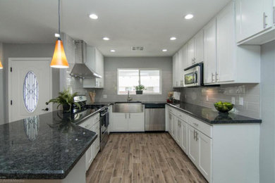Example of a mid-sized u-shaped open concept kitchen design in Phoenix with recessed-panel cabinets, white cabinets, gray backsplash, subway tile backsplash, stainless steel appliances and no island