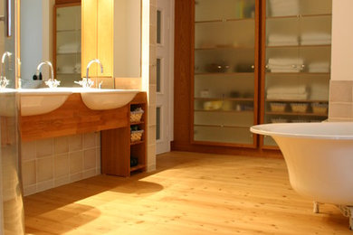 Großes Klassisches Badezimmer mit Glasfronten, dunklen Holzschränken, freistehender Badewanne, Urinal, Keramikfliesen, hellem Holzboden, Aufsatzwaschbecken und Waschtisch aus Holz in München