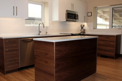 Mid-sized minimalist u-shaped light wood floor eat-in kitchen photo in Other with an undermount sink, flat-panel cabinets, dark wood cabinets, quartz countertops, white backsplash, ceramic backsplash, stainless steel appliances and an island