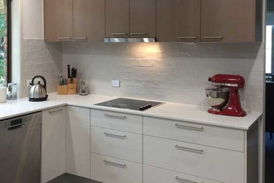Photo of a mid-sized contemporary u-shaped open plan kitchen in Brisbane with a double-bowl sink, medium wood cabinets, quartz benchtops, white splashback, ceramic splashback, stainless steel appliances, ceramic floors and a peninsula.