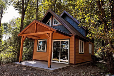 Inspiration for a small rustic blue two-story wood and clapboard exterior home remodel in New York with a metal roof and a brown roof