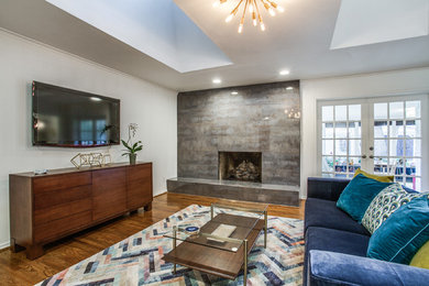 1950s medium tone wood floor and brown floor living room photo in Dallas with white walls, a standard fireplace and a wall-mounted tv