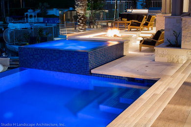 Example of a mid-sized trendy backyard stone and rectangular infinity hot tub design in Orange County