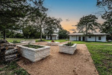 This is an example of a mid-sized rustic drought-tolerant and full sun backyard gravel and metal fence landscaping in Houston with a fire pit for spring.