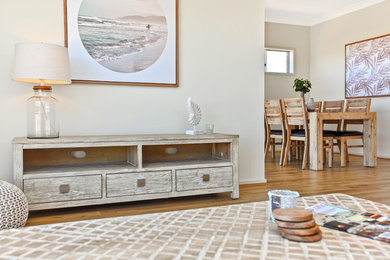 This is an example of a mid-sized beach style open concept living room in Adelaide with beige walls, medium hardwood floors, no tv and brown floor.