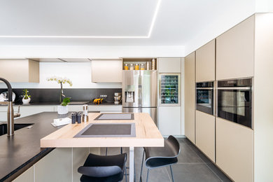 Design ideas for a mid-sized contemporary l-shaped separate kitchen in Toulouse with beige cabinets, with island, black floor, black benchtop, a single-bowl sink, beaded inset cabinets, marble benchtops, white splashback, black appliances and cement tiles.