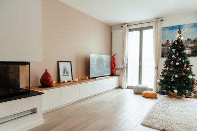Cette image montre une salle de séjour design ouverte avec une bibliothèque ou un coin lecture, un mur beige, parquet clair, une cheminée d'angle, un manteau de cheminée en plâtre, un téléviseur indépendant et un sol beige.