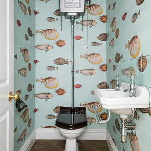 Photo of a coastal cloakroom in London with a wall-mounted sink, a two-piece toilet, multi-coloured walls and dark hardwood flooring.