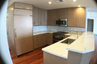 Medium sized contemporary u-shaped kitchen in Hawaii with flat-panel cabinets, engineered stone countertops, medium hardwood flooring and an island.