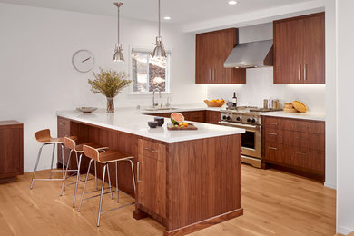 Photo of a small contemporary u-shaped eat-in kitchen in San Francisco with flat-panel cabinets, quartz benchtops, stainless steel appliances, medium hardwood floors, a double-bowl sink, dark wood cabinets, white splashback, stone slab splashback, a peninsula and brown floor.