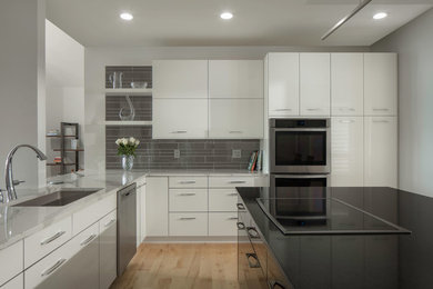Inspiration for a mid-sized contemporary u-shaped light wood floor and beige floor eat-in kitchen remodel in Atlanta with an undermount sink, flat-panel cabinets, white cabinets, quartzite countertops, gray backsplash, glass tile backsplash, stainless steel appliances, an island and white countertops