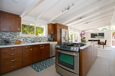 Example of a large minimalist u-shaped ceramic tile eat-in kitchen design in Los Angeles with a drop-in sink, flat-panel cabinets, dark wood cabinets, granite countertops, gray backsplash, glass tile backsplash, stainless steel appliances and an island