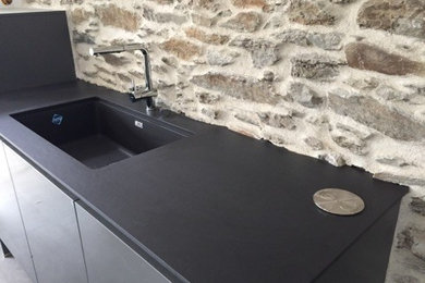 Foto di una grande cucina design con lavello sottopiano, ante lisce, ante grigie, top in granito, paraspruzzi nero e elettrodomestici da incasso