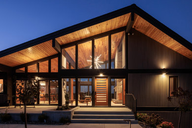 Inspiration for a mid-sized 1960s black one-story concrete fiberboard and board and batten exterior home remodel in Minneapolis with a shingle roof and a black roof