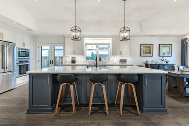 Inspiration for a large transitional l-shaped dark wood floor and coffered ceiling eat-in kitchen remodel in Toronto with an undermount sink, shaker cabinets, white cabinets, quartz countertops, white backsplash, porcelain backsplash, stainless steel appliances, an island and white countertops