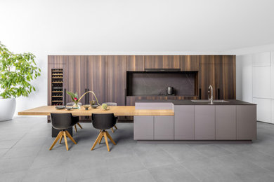 Immagine di una cucina minimalista con lavello sottopiano, ante a filo, ante grigie, top in superficie solida, top nero e paraspruzzi nero