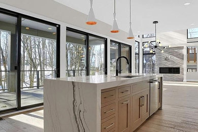 Inspiration for a mid-sized contemporary u-shaped light wood floor and brown floor eat-in kitchen remodel in Indianapolis with an undermount sink, flat-panel cabinets, light wood cabinets, quartz countertops, stainless steel appliances, an island and white countertops