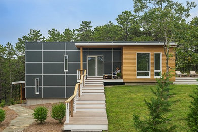 This is an example of a small contemporary two-storey black house exterior in Boston with a flat roof and mixed siding.