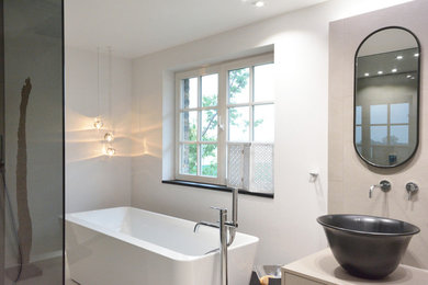Mittelgroßes Modernes Badezimmer mit flächenbündigen Schrankfronten, schwarzen Schränken, freistehender Badewanne, bodengleicher Dusche, Wandtoilette mit Spülkasten, beigen Fliesen, Steinfliesen, beiger Wandfarbe, Keramikboden, Aufsatzwaschbecken, beigem Boden, offener Dusche und schwarzer Waschtischplatte in Köln